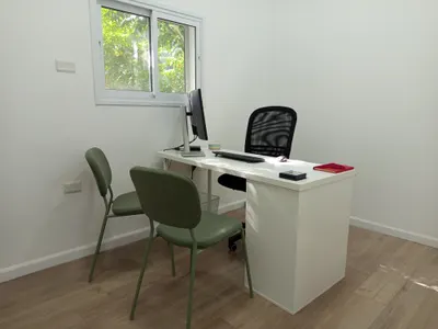 חדר טיפולים מואר, עם שולחן וכיסאות מול החלון.
